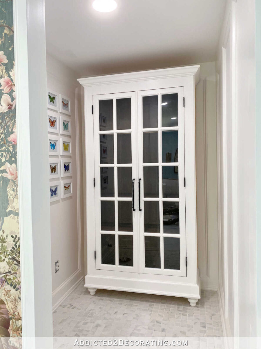 Finished DIY storage cabinet with glass French doors, crown molding, and furniture feet -- dark stained interior and white painted exterior